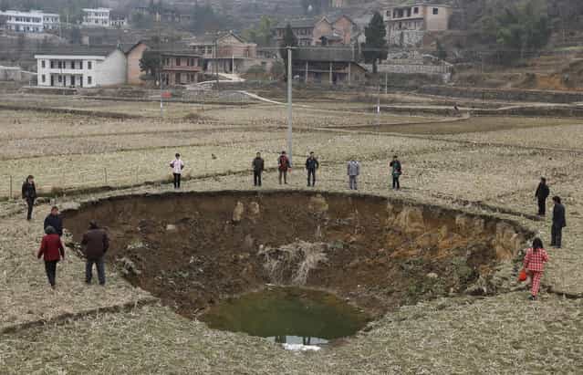 People stand by a recent caved-in area on a paddy field in Fukou county, Hunan province, January 12, 2013. More than 20 pits formed from the sunken ground surface in Fukou county during the past four months. According to the local media, the government's initial investigation showed years of mining destroyed the local underground water systems and led to the numerous cave-ins. (Photo by Reuters/China Daily)