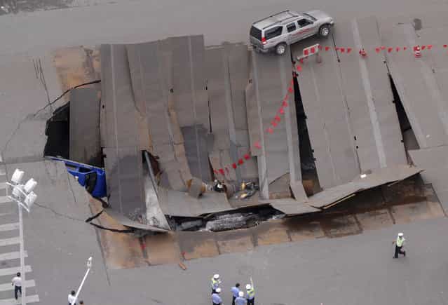 Policemen check a collapsed section of a crossroad in Hefei, Anhui province August 8, 2009. A taxi and a few motorbikes fell into the hole, local media reported. (Photo by Reuters/China Daily)