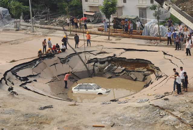 A stranded car is hoisted from a collapsed road surface in Guangzhou, Guangdong province, September 7, 2008. The road collapsed on Sunday afternoon and trapped the car in a hole, which measured 5 meters (16.4 feet) in depth and 15 meters (49.2 feet) in diameter, local media reported. Further investigation is underway. Picture taken September 7, 2008. (Photo by Reuters/China Daily)