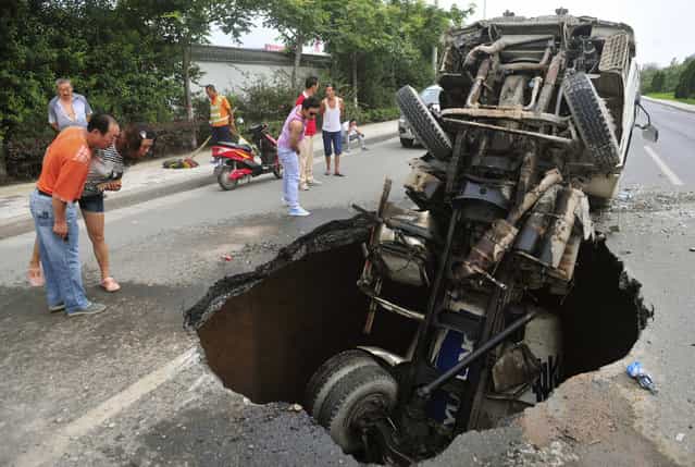 People look at a tanker after it fell into a caved-in area on a road in Xi'an, Shaanxi province, July 27, 2013. No casualty was reported in the accident, according to local media. (Photo by Reuters/Stringer)