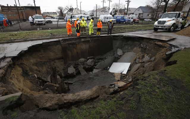 Workers look into a sinkhole caused by a broken water main in Chicago, Illinois, April 18, 2013. Heavy rains and flooding brought havoc to the Chicago area on Thursday, shutting major expressways, delaying commuter trains for hours, cancelling flights, flooding basements and closing dozens of suburban schools. On the city's South Side, a sinkhole opened up on a residential street, swallowing three cars, according to Officer Mike Sullivan of the Chicago Police Department. One person was hospitalized with non-life-threatening injuries. (Photo by Jim Young/Reuters)