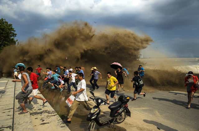 Visitors run away as waves from a tidal bore surge past a barrier on the banks of Qiantang River, in Hangzhou Zhejiang province, on August 24, 2013. (Photo by Reuters/Stringer via The Atlantic)