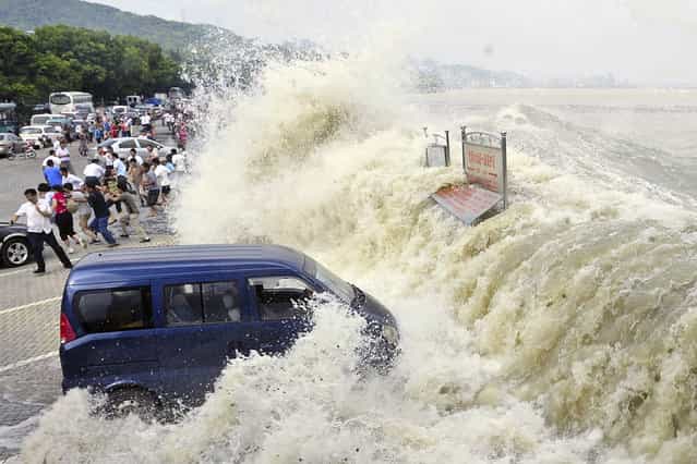 Spectators flee as waves created by a tidal bore crash over a barrier on the Qiantang river at Hangzhou, in east China's Zhejiang province, on August 31, 2011. (Photo by AP Photo via The Atlantic)