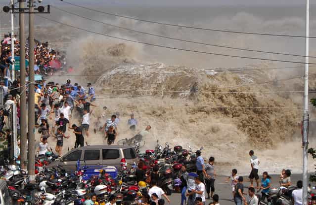 A crowd of Chinese tourists run away as a tidal bore breaks through the dam by the Qiangtang River in Haining, east China's Zhejiang province on August 31, 2011. Visitors gather to experience the Qianjiang Tidal Bore from early morning, an annual tradition for the residents living nearby. (Photo credit should read STR/AFP Photo)