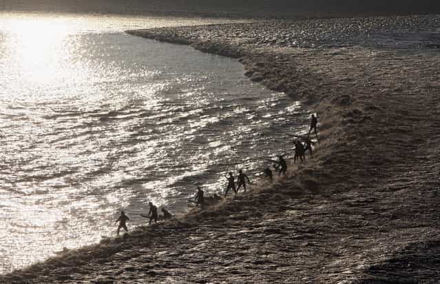 Surfers enjoy the Severn Bore near Newnham along the River Severn on March 2, 2010 in Gloucestershire, England. (Photo by Matt Cardy/Getty Images via The Atlantic)