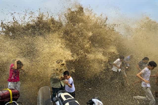 Visitors run away from a tidal bore wave as it surges over a barrier on the banks of Qiantang River, in Hangzhou Zhejiang province, on August 25, 2013. (Photo by Reuters/Stringer via The Atlantic)