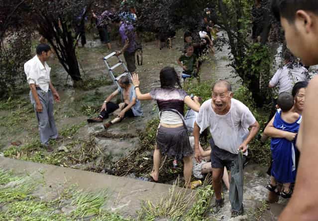 Spectators get to their feet, after being swept down a hill by huge waves while watching tides of Qiantang River on August 22, 2013 in Haining, China. (Photo by ChinaFotoPress via The Atlantic)