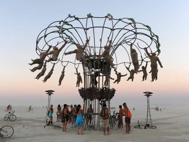 People bang on drums to make monkey effigies spin in an interactive sculpture at the Burning Man festival in Gerlach, Nev. on Friday, Aug. 30, 2013. Once a year, tens of thousands of participants gather in Nevada's Black Rock Desert for the counterculture event. (Photo by Andy Barron/AP Photo/Reno Gazette-Journal)