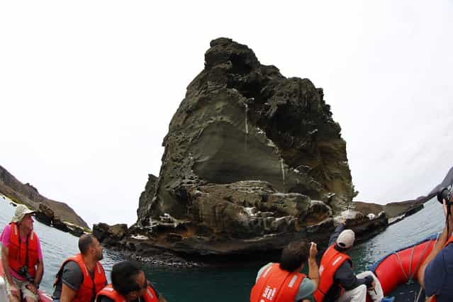 Tourists ride a boat as they look at the pinnacle rock at Bartolome Island in Galapagos August 23, 2013. (Photo by Jorge Silva/Reuters)