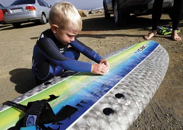 Triston waxes his surfboard before hitting the waves. (Photo by Joe Johnston/The Tribune of San Luis Obispo)