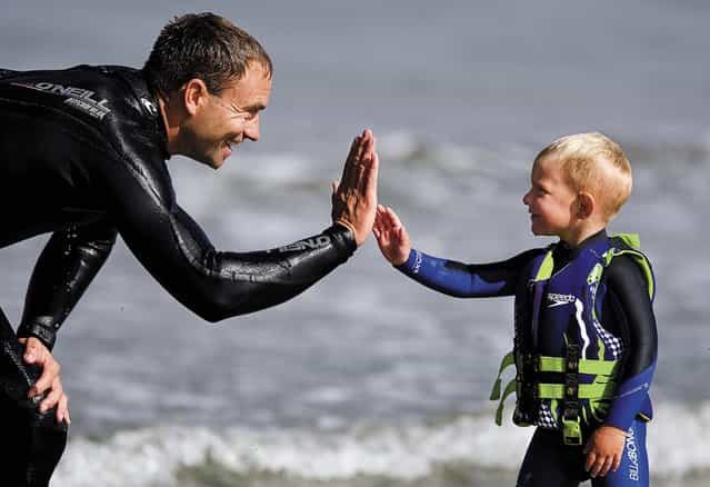 Triston gets a high five from his father after riding all the way to the sand. (Photo by Joe Johnston/The Tribune of San Luis Obispo)