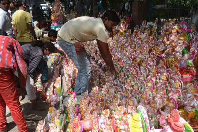 Indians shop for idols of the Hindu god Lord Ganesh ahead of the Ganesh Chaturthi festival in New Delhi on September 7, 2013. The Hindu festival which celebrates the rebirth of the God Lord Ganesha, begins this year on September 9 and culminates on September 19, with many of the statues being immersed in bodies of water. (Photo by AFP Photo/Raveendran)