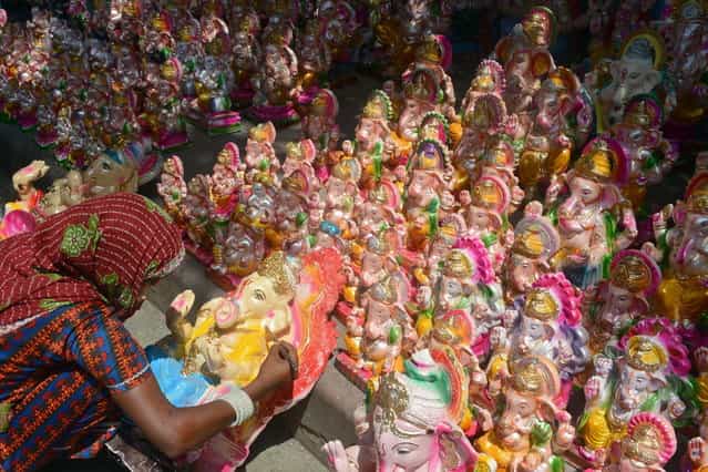 An Indian artisan decorates an idol of Hindu god Lord Ganesh at a roadside market ahead of the Ganesh Chaturthi festival in New Delhi on September 7, 2013. The Hindu festival which celebrates the rebirth of the God Lord Ganesha, begins this year on September 9 and culminates on September 19, with many of the statues being immersed in bodies of water. (Photo by AFP Photo/Raveendran)