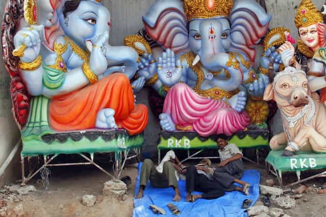 Indian artisans take a nap near idols of elephant-headed Hindu God Ganesha being prepared for Ganesh Chaturthi festival at a workshop in Hyderabad, India, Thursday, September 5, 2013. Ganesh Chaturthi, which begins from September 9, is celebrated as the birthday of Lord Ganesha who is widely worshiped by Hindus as the god of wisdom, prosperity and good fortune. (Photo by Mahesh Kumar A./AP Photo)