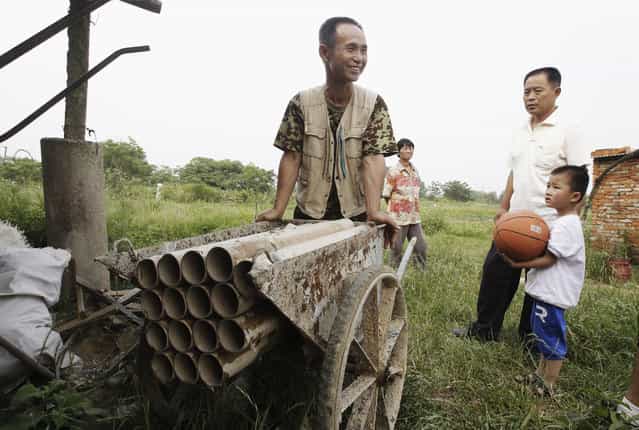 Chinese farmer Yang Youde pushes his homemade cannon near his farmland on the outskirts of Wuhan, Hubei province June 6, 2010. Yang's cannon, which is made out of a wheelbarrow, pipes and firing rockets, is used to defend his fields against property developers who wants his land. (Photo by Reuters/Stringer)