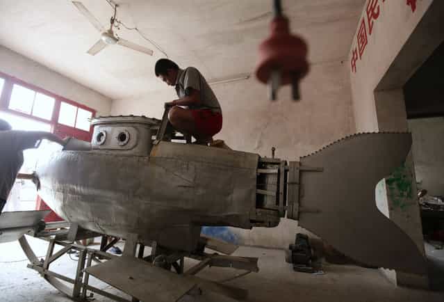 A worker polishes the surface of an unfinished miniature submarine at a workshop of Zhang Wuyi, a local farmer who is interested in scientific inventions, in Qingling village, on the outskirts of Wuhan, capital of central China's Hubei province August 29, 2011. Zhang has successfully tested his self-made miniature submarine "Shuguang Hao", which is 3.6 m (12 feet) long, 1.8 m (6 feet) high, has a maximum diving depth of 20 m (65 feet), can travel at a speed of 20 km per hour for 10 hours underwater and is shaped as a dolphin. [I hope to sell my submarine as a civil product with the price of about 100,000 yuan ($15,670) after safety tests, and a merchant has decided to order one in this month], Zhang said. (Photo by Jason Lee/Reuters)