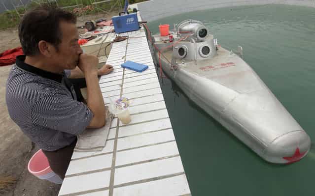 An engineer working for Zhang Wuyi looks at a double-seater submarine during a test operation at an artificial pool near a shipyard in Wuhan, Hubei province May 7, 2012. (Photo by Reuters/Stringer)