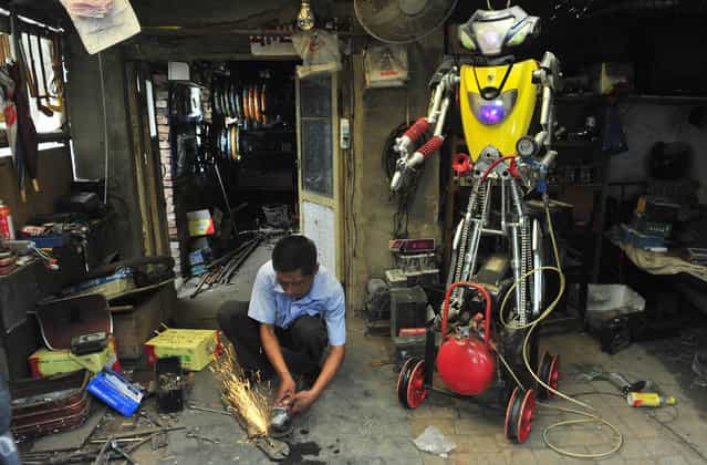 A 49-year-old electric bike mechanic who identified himself only as Wu welds a component to fit onto his newly-made robot (R) at his repair shop in Shenyang, Liaoning province June 25, 2012. Wu spent over 10 days to make this nearly two-meter high robot using parts from abandoned electric bikes. The robot, which is able to walk and pump up tires by itself, is still under modification, according to local media. (Photo by Reuters/Stringer)