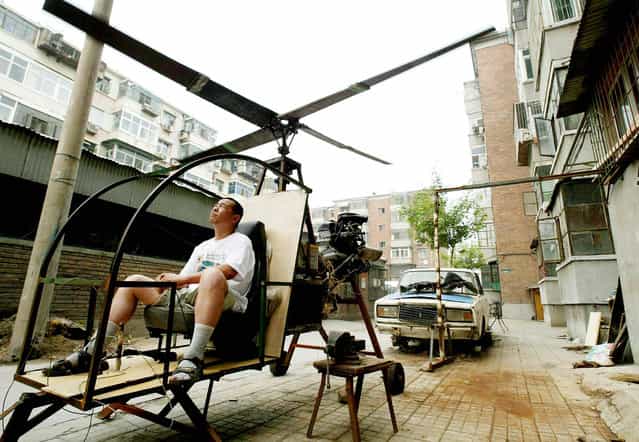 A self-styled Chinese inventor tests his homemade helicoptor next to his apartment in Beijing June 25, 2003. Yu Jun follows in the footsteps of his younger brother who lost his life in a national park in central China at the end of a 20 year search for the legendary [Bigfoot], and intends to continue the quest from the sky. Without any formal education in aerospace science, Yu Jun spent five years constructing the helicopter from spare parts belonging to a dilapidated [Lada] automobile (in back). (Photo by Reuters/China Photo)