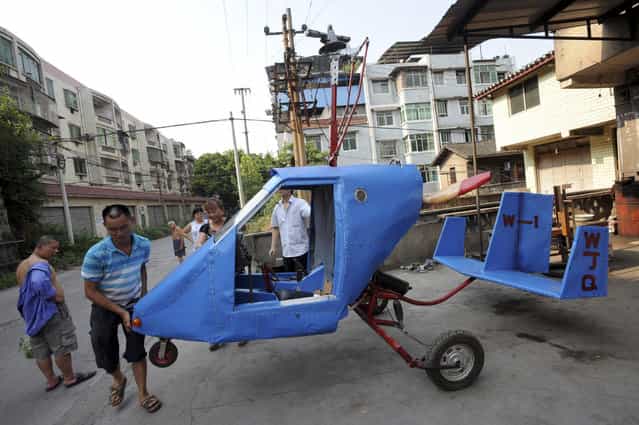 Wen Jiaquan (2nd L), 54-year-old motorcycle mechanic, moves his self-made helicopter in Qingping township of Chongqing municipality, July 28, 2013. Wen and his family spent over 10,000 yuan (1,630 USD) and more than three months to build this 4.2-metre-long, 2.8-metre-high helicopter using mostly motorcycle components and a used car engine, local media reported. (Photo by Reuters/Stringer)