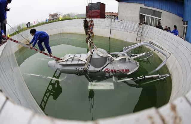 A worker climbs up from Zhang Wuyi's newly designed unmanned submarine that captures sea cucumbers, during a test operation at an artificial pool near a shipyard in Wuhan, Hubei province, March 26, 2013. Zhang, a 38-year-old local farmer who is interested in scientific inventions, has independently made eight miniature submarines with several fellow engineers, one of which was sold to a businessman in Dalian at a price of 100,000 yuan ($15,855) in 2011. The submarines, mainly designed for harvesting aquatic products, such as sea cucumber, have a diving depth of 20-30 metres (66-98 feet), and can travel for 10 hours, local media reported. (Photo by Reuters/Stringer)