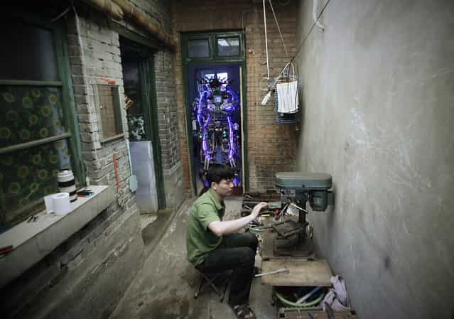 Chinese inventor Tao Xiangli welds a component of his self-made robot (back) at the yard of his house in Beijing, May 15, 2013. Tao, 37, spent about 150,000 yuan (USD 24,407 ) and more than 11 months to build the robot out of recycled scrap metals and electric wires that he bought from a second-hand market. The robot is 2.1-metre-tall and around 480 kilograms (529 lbs) in weight, local media reported. (Photo by Suzie Wong/Reuters)