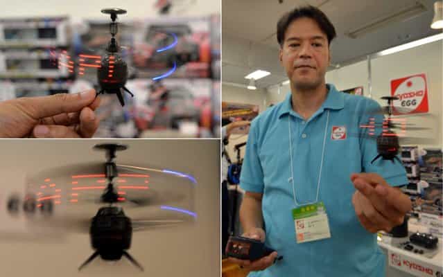 Japan's toy maker Kyosho employee displays the company's palm sized infrared controlled drone 'Neon Messenger', which can displays LED messages while flying at a toy trade show in Tokyo on September 11, 2013. Kyosho will put it on the market end of this month for the Christmas gift. (Photo by Yoshikazu Tsuno/AFP Photo)