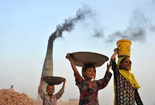 Afghan children carry collected coal from a brick factory for their home on the outskirts of Jalalabad on September 9, 2013. Some nine million Afghans or 36 percent of the population are living in [absolute poverty] while another 37 percent live barely above the poverty line, according to a UN report. (Photo by Noorullah Shirzada/AFP Photo)