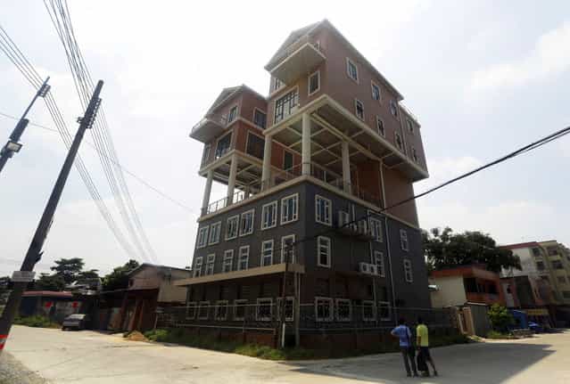 People looks at houses on the rooftop of a factory building in Dongguan, Guangdong province, September 10, 2013. According to local media, the government said the size of the houses was not in line with the original design submitted, thus the construction should be deemed illegal. The houses were completed two years ago. (Photo by Reuters/Stringer)