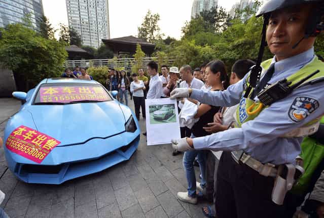 A policeman shows a paper bearing a registration photo of a Hyundai Coupe car which was later refitted into a knockoff Lamborghini (L) parked on a pedestrian street in Chongqing municipality, September 12, 2013. Police towed the car away on the charge of illegal parking on Thursday after failing to contact the owner. A placard under the car windshield reads, [This refitted Lamborghini car on sale, starting price 98,000 yuan (16,018 USD)], local media reported. (Photo by Reuters/Stringer)