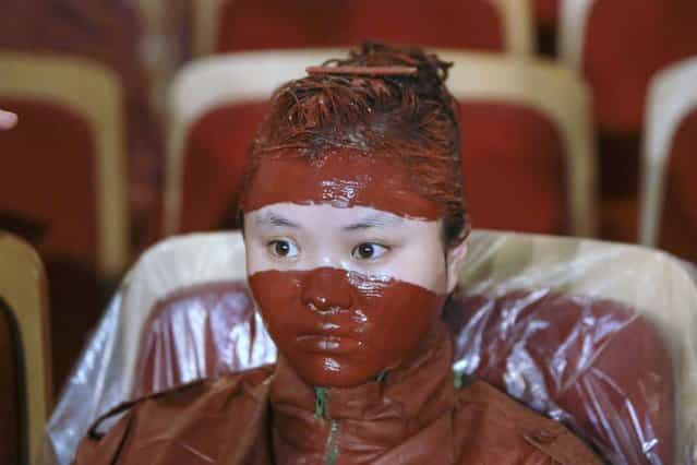 A participant waits for the finishing touches to her makeup after she was painted for Liu Bolin's latest project in Beijing. September 12th, 2013. (Photo by Jason Lee/Reuters)