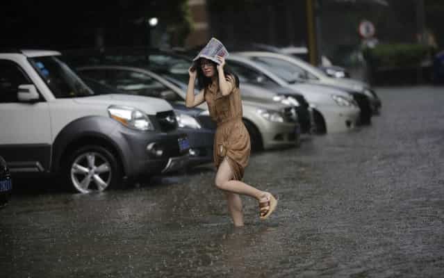 A woman walks on the flooded street from a heavy thunderstorm in Shanghai, China, Friday, September 13, 2013. Sudden and heavy thunderstorm hit the city in the afternoon Shanghai and caused the flood with rain water over many streets. (Photo by Eugene Hoshiko/AP Photo)