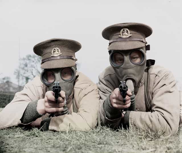 Soldiers of the Royal Norfolk Regiment at Aldershot, Hampshire getting used to revolver shooting while wearing a gas mask. UK, 28th March 1936.