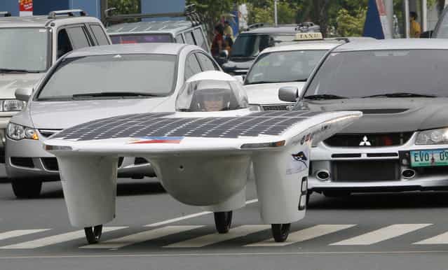 Eric Tan, one of the students who designed and constructed the first Philippine solar-powered car, drives past vehicles along a street in Manila September 1, 2007, after it was unveiled. (Photo by Romeo Ranoco/Reuters)