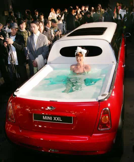 A model wearing a bikini soaks in a jacuzzi on the rear end of a limousine named [Mini XXL] at the Japanese designers' brand THEATRE PRODUCTS Fall Winter 2005 collection, at the National stadium in Tokyo April 6, 2005. The six metre (about 20 feet) long stretch Mini Cooper S, equipped with six wheels, four doors, six passenger seats and a jacuzzi, is touring around Europe and parts of Asia where it is set to be the star attraction at various events, the organizers said. (Photo by Issei Kato/Reuters)