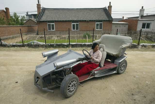 Zhang Jinduo's wife tries on a self-made racing car on the outskirts of Shenyang, Liaoning province May 10, 2008. Zhang, the 53-year-old local farmer made the racing car with the help of his son who is a car mechanic. The car is equipped with a rear-mounted motorcycle engine and can achieve 60-80 km per hour, according to local media. (Photo by Reuters/Stringer)