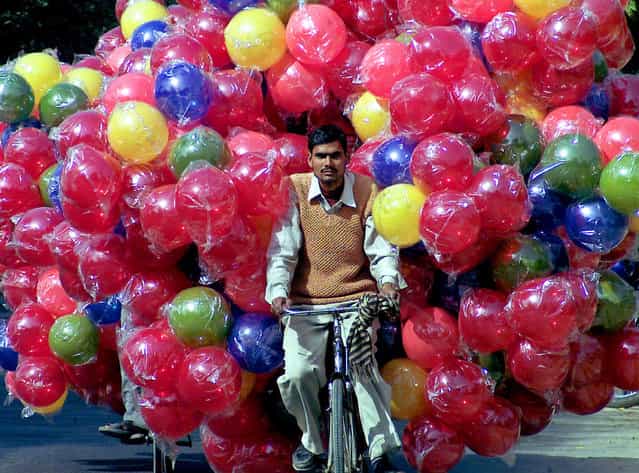 An Indian man carries plastic balls on his bicycle in the northern Indian city Lucknow February 16, 2006. (Photo by Pawan Kumar/Reuters)