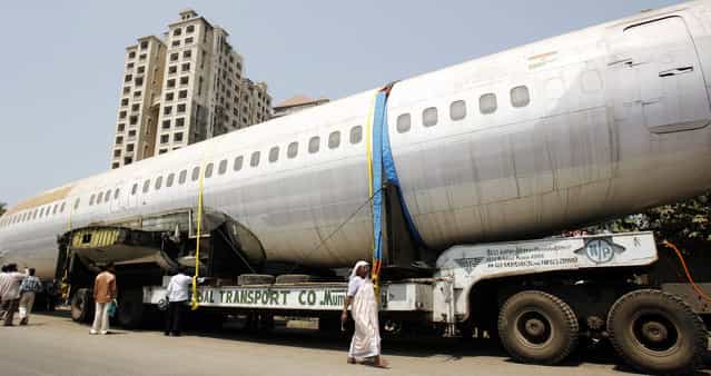 People walk past the fuselage of a Boeing 737 parked on a road in Mumbai May 3, 2007. The trailer carrying the fuselage got stuck on a narrow road in Mumbai three days ago while being taken to New Delhi. (Photo by Arko Datta/Reuters)