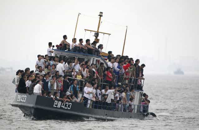 North Koreans look at a Chinese boat for tourists on Yalu River near the North Korean town of Sinuiju July 27, 2010. (Photo by Jacky Chen/Reuters)