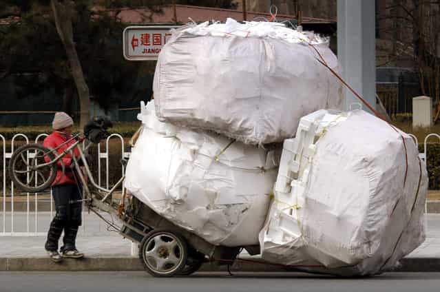 A recyclable materials collector stands in front of her overloaded tricycle on a main street in central Beijing March 12, 2010. (Photo by David Gray/Reuters)