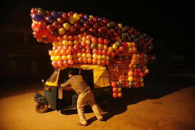 A man pushes an auto-rickshaw loaded with plastic balls to sell at a wholesale market in New Delhi November 10, 2011. (Photo by Parivartan Sharma/Reuters)