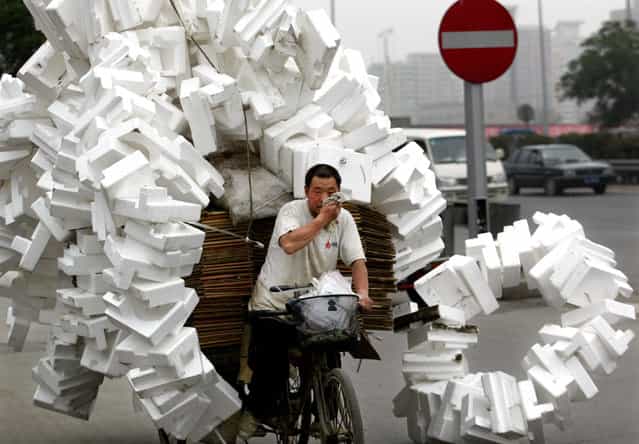 A Chinese man transfers recyclable rubbish which he collects from streets with a three-wheeled flat-bed bicycle in Beijing June 28, 2002. (Photo by Reuters/China Photo)
