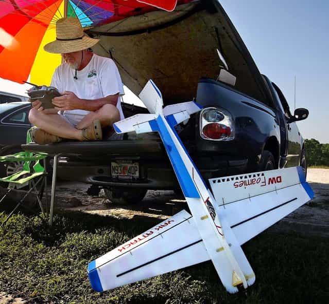 Phil Petty examines his multiple channel radio control as his plane rests next to him at Phil Wherry Field. [I have a bunch of hubbies], Petty said, [but in particular these (RC Bush Pilots) are a great bunch of people]. (Photo by Bill Ingram/The Palm Beach Post)