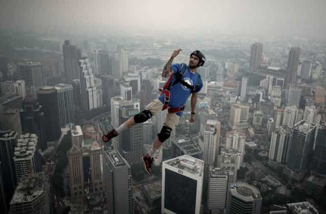 Base jumper Theo Gagliardini from France leaps from the 300-meters Open Deck of the Malaysia's landmark Kuala Lumpur Tower during the International Tower Jump in Kuala Lumpur on September 27, 2013. (Photo by Mohd Rasfan/AFP Photo)