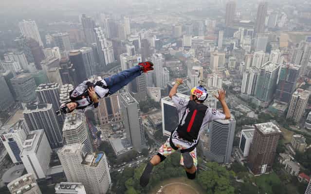 Base jumper Jean-Philippe Marie Teffaud, left, and his team mate Frederic Yves Fugen of France leap from the 300-meter Open Deck of the Malaysia's landmark Kuala Lumpur Tower during the International Tower Jump in Kuala Lumpur, Friday, September 27, 2013. About 103 professional base jumpers from 20 countries took part in the annual event. (Photo by Vincent Thian/AP Photo)