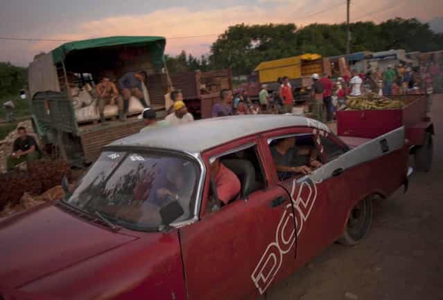 In this September 25, 2013 photo, a merchant drives away his classic American car pulling a small trailer loaded with bananas, tomatoes and onions at the 114th Street Market on the outskirts of Havana, Cuba. Produce is brought in by growers themselves and by transportation specialists who make a living by buying crops far away and hauling them to Havana, the island s biggest and most important market. (Photo by Ramon Espinosa/AP Photo)