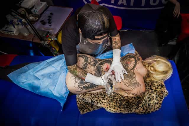 Receiving a specialist artwork tattoo at the 9th London International Tattoo Convention. The 9th London International Tattoo Convention, one of the most prestigious body art conventions in the world, brought together 300 of the best tattoo artists to thousands of admirers at the Tobacco Dock. (Photo by Guy Corbishley/Demotix/Corbis)