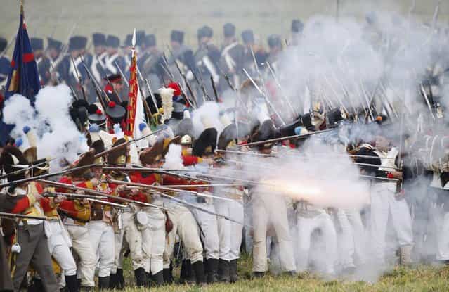 Performers wearing 19th century French military uniforms fire their weapons as they attack Allied forces during a reenactment of the Battle of the Nations, in a field in the village of Markkleeberg near Leipzig October 20, 2013. The east German city of Leipzig commemorated the 200th anniversary of the largest battle of the Napoleonic Wars on Sunday by reenacting the Battle of the Nations, with 6,000 military-historic association enthusiasts from all over Europe. The decisive encounter in which tens of thousands of soldiers were killed, took place from October 17-19, 1813, just outside of Leipzig. At the height of the hostilities Napoleon fielded more than 200,000 men against an Allied force of some 360,000 soldiers which included troops from Russia, Austria, Prussia and Sweden. (Photo by Fabrizio Bensch/Reuters)