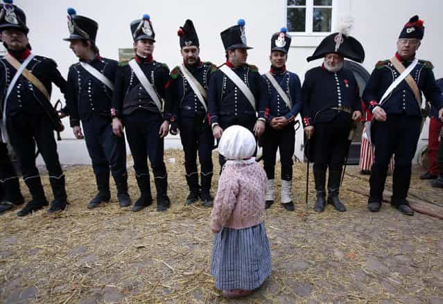 A little girl walks past performers wearing 19th century French military uniform at a bivouac camp for the reenactment of the Battle of the Nations in the village of Markkleeberg near Leipzig October 19, 2013. The east German city of Leipzig is commemorating the 200th anniversary of the largest battle of the Napoleonic Wars on Sunday by reenacting the Battle of Nations, with 6,000 military-historic association enthusiasts from all over Europe. Some 185,000 French troops and 320,000 allied troops from Austria, Prussia, Russia and Sweden, entered into the decisive battle just outside Leipzig on October 16, 1813. (Photo by Fabrizio Bensch/Reuters)