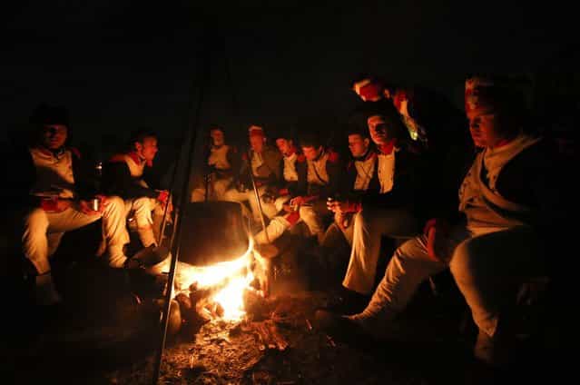 Performers wearing 19th century French military uniform sit around a fire at a bivouac camp for the reenactment of the Battle of the Nations in the village of Markkleeberg near Leipzig October 19, 2013. The east German city of Leipzig is commemorating the 200th anniversary of the largest battle of the Napoleonic Wars on Sunday by reenacting the Battle of Nations, with 6,000 military-historic association enthusiasts from all over Europe. Some 185,000 French troops and 320,000 allied troops from Austria, Prussia, Russia and Sweden, entered into the decisive battle just outside Leipzig on October 16, 1813. (Photo by Fabrizio Bensch/Reuters)